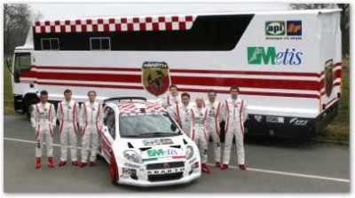 Vettura da competizione e squadra davanti al mezzo di assistenza.