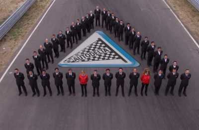 Foto di gruppo dello staff sul rettilineo, logo Autodelta a terra.